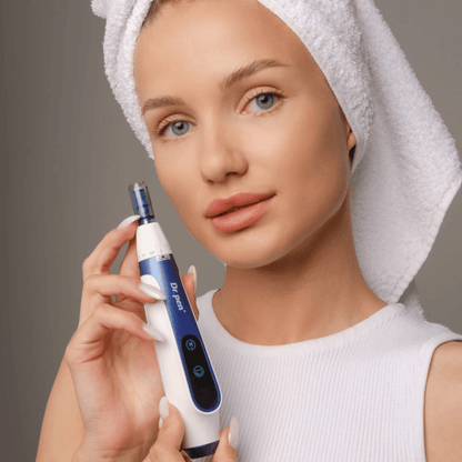 Vrouw met handdoek om haar haar houdt een Dr. Pen A11 microneedling-pen vast – een professioneel huidverzorgingsapparaat voor een gladdere en stevigere huid.